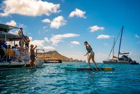 Guest standing on a paddleboard with Diamond Head behind