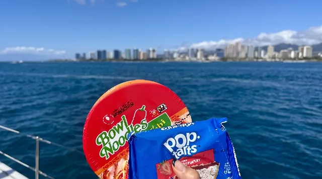 Cup noodles and Pop-Tarts held up against the Waikiki sea